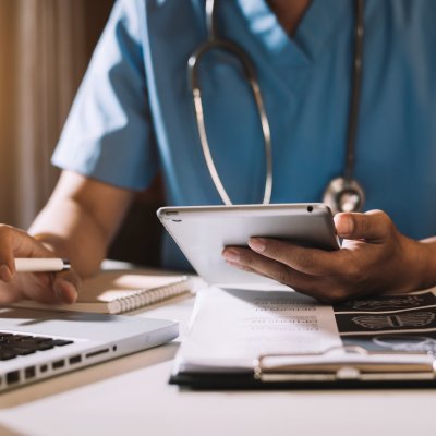 Doctor embracing digital health, working on laptop and iPad 